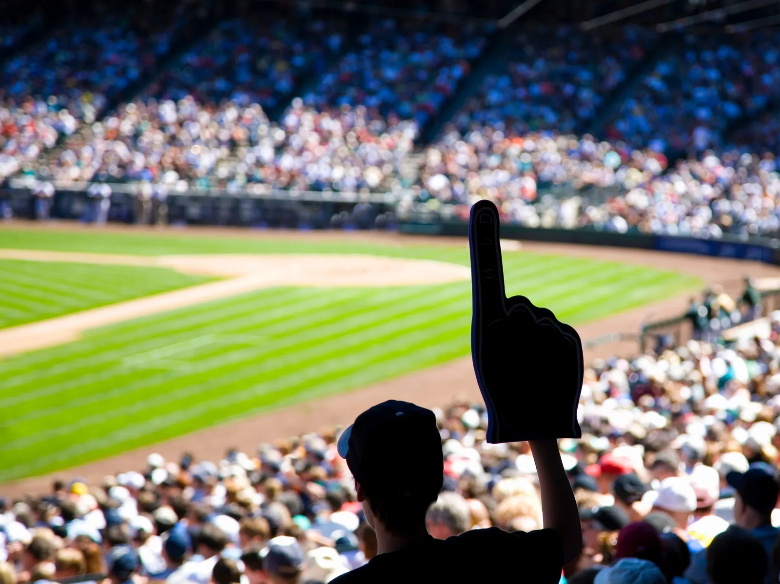 A fan in a packed stadium crowd holding up a foam finger.